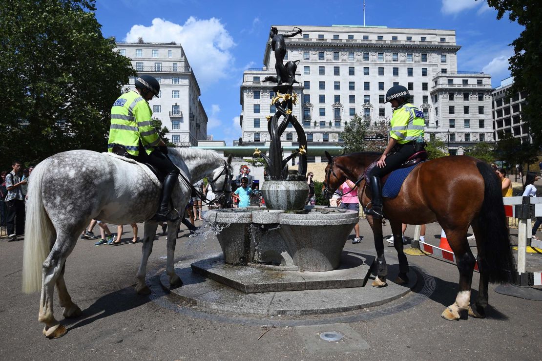 Police officers water their horses at a fountain in London's Green Park.