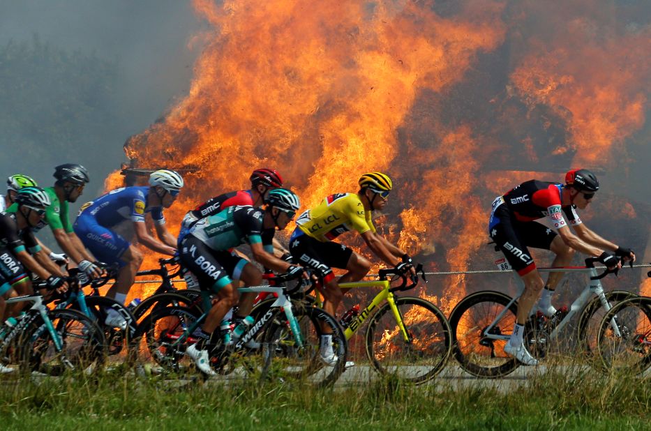 A pack rides by a burning haystack during the sixth stage on July 12.