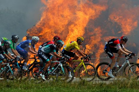 A pack rides by a burning haystack during the sixth stage on July 12.