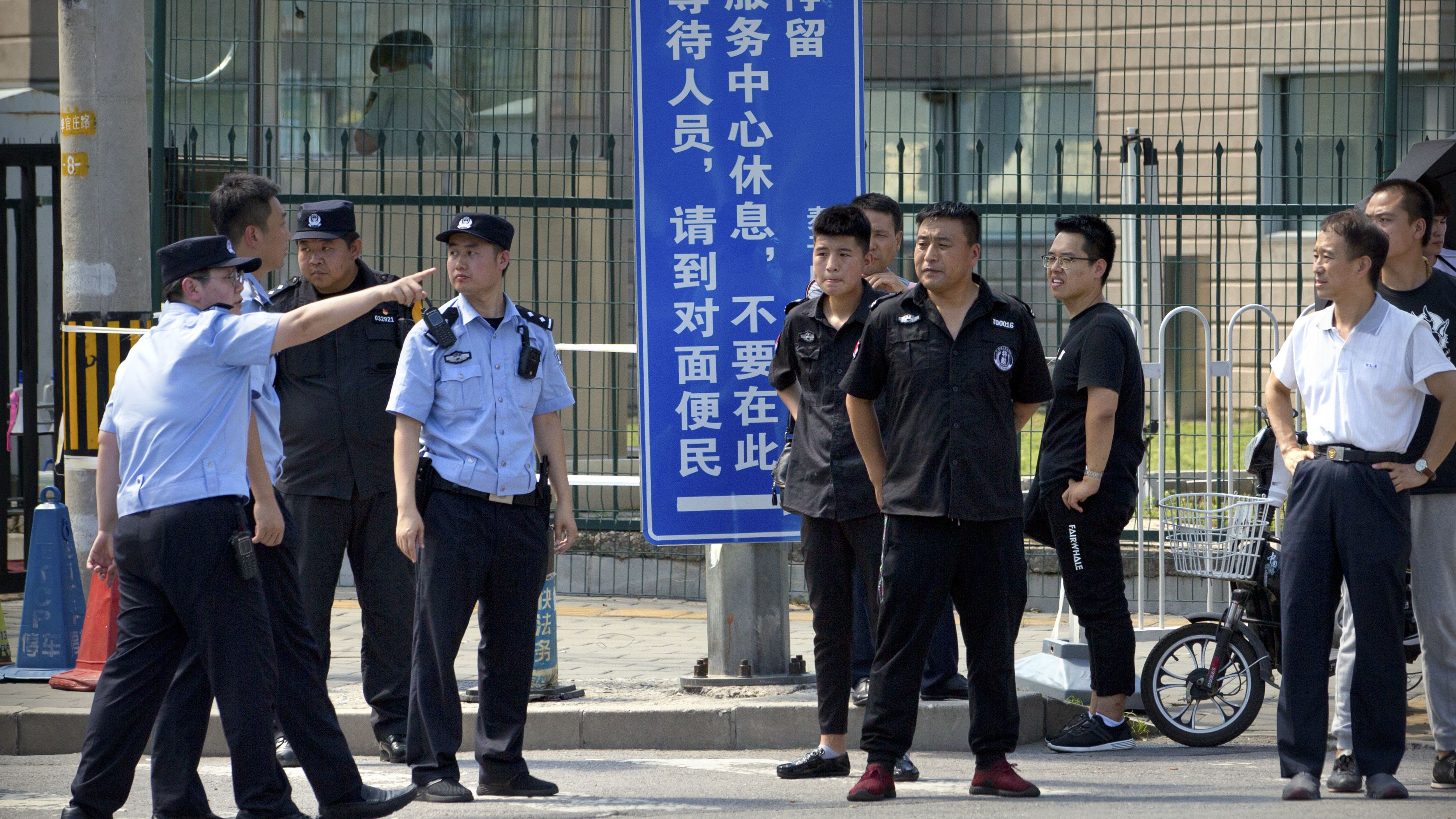 Chinese security personnel stand outside the U.S. Embassy, in the background, after a reported blast occurred nearby on July 26.