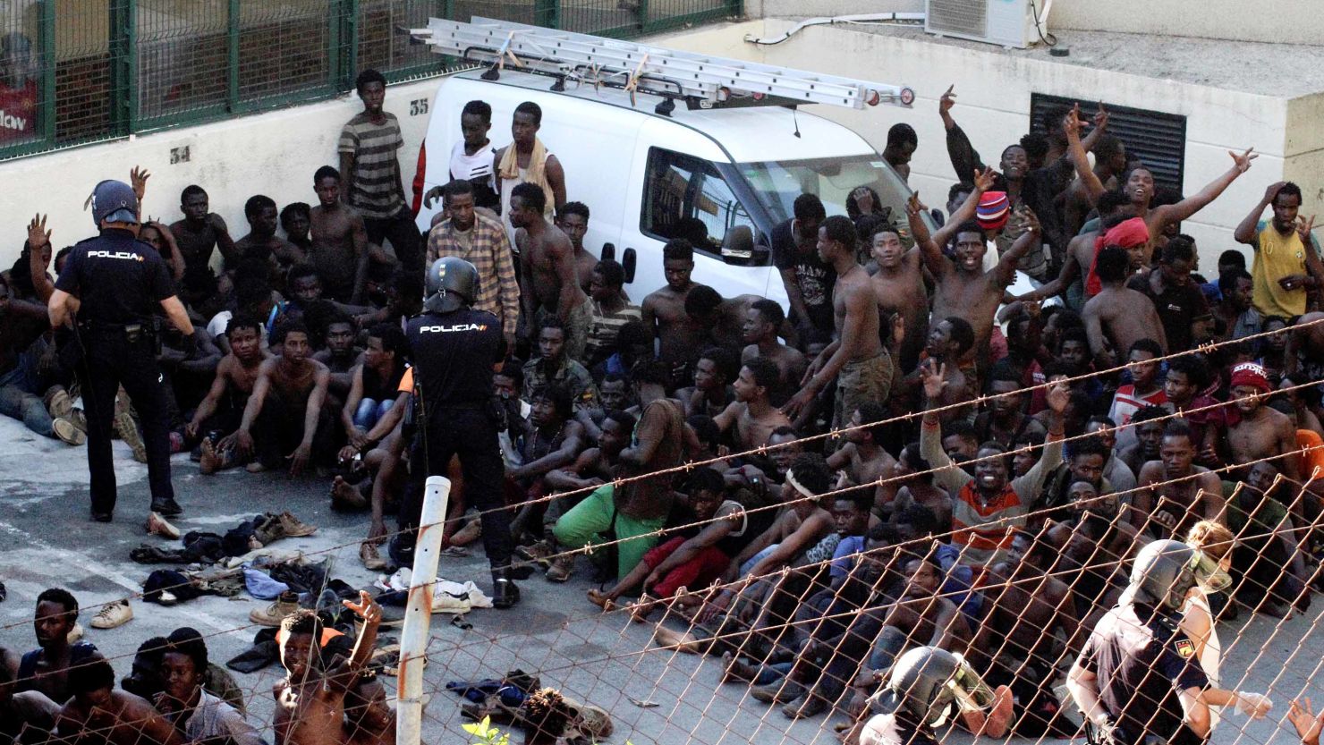 Police officers keep watch over some of the migrants who managed to breach the border fence.