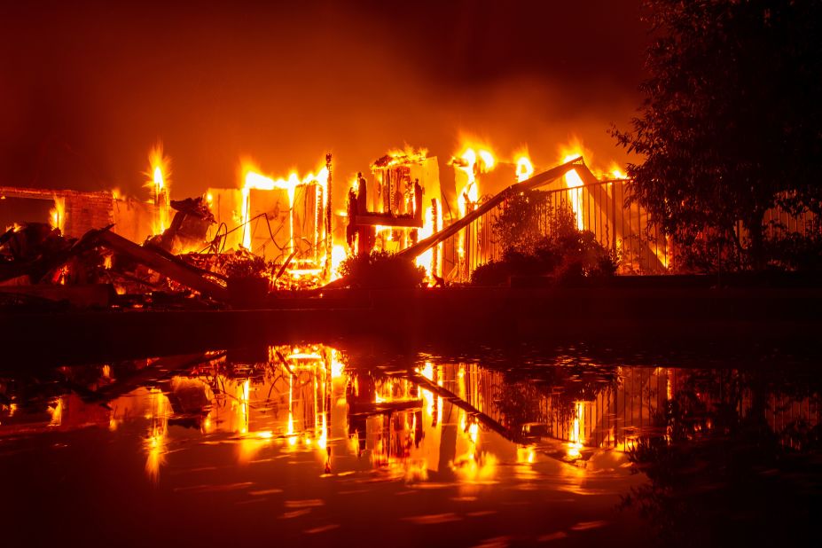 A burning home is reflected in a pool in Redding on July 27.