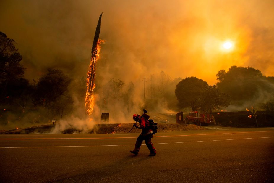 A firefighter walks along Highway 299 as the Carr Fire tears through Shasta on July 26.