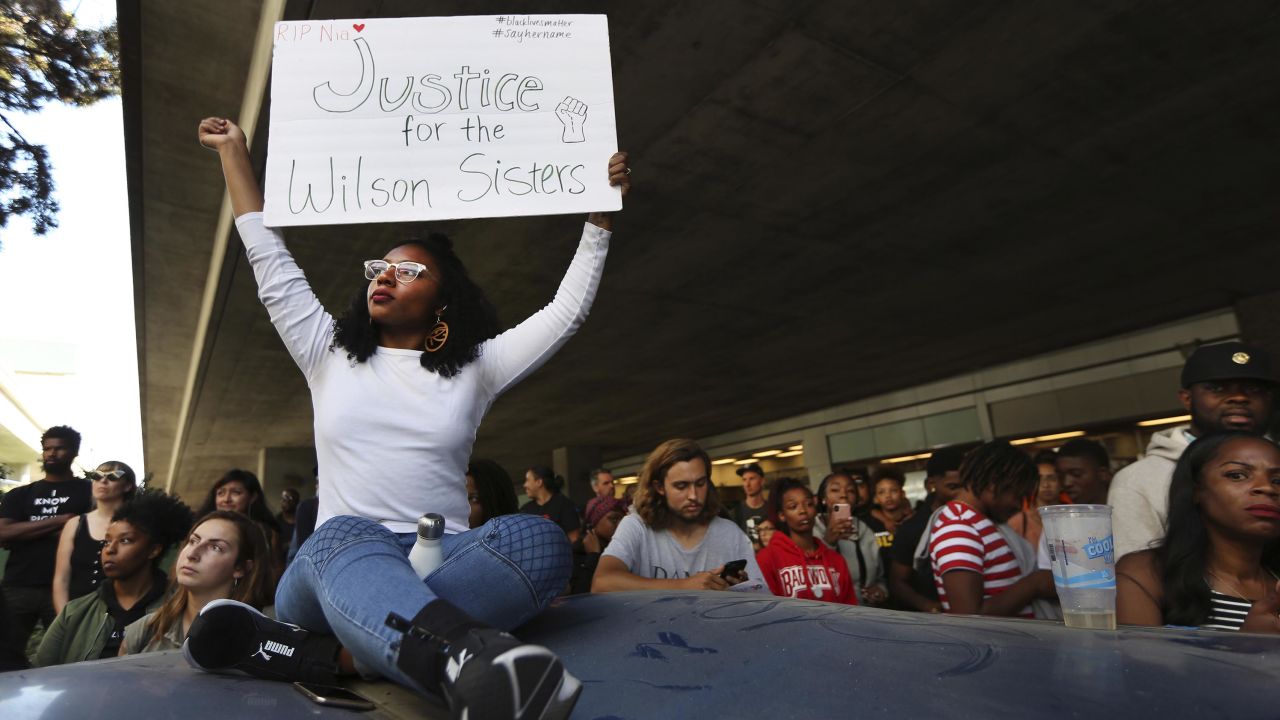Jasmine Malone, 23, holds a sign at a vigil held for 18-year-old Nia Wilson, who was stabbed to death the night before at the MacArthur BART station in Oakland, California, on Monday, July 23, 2018.