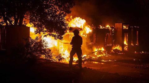 A firefighter battles the fast-moving Carr Fire on Thursday at a house in Redding, California.