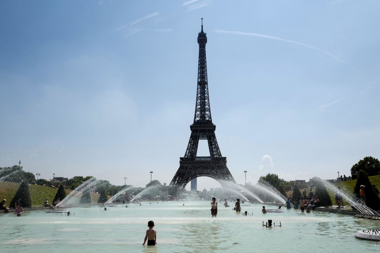 People cool themselves at the Trocadero Fountain, in front of the Eiffel Tower in Paris on Friday, July 27.