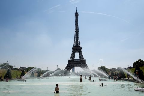 People cool themselves at the Trocadero Fountain, in front of the Eiffel Tower in Paris on Friday, July 27.