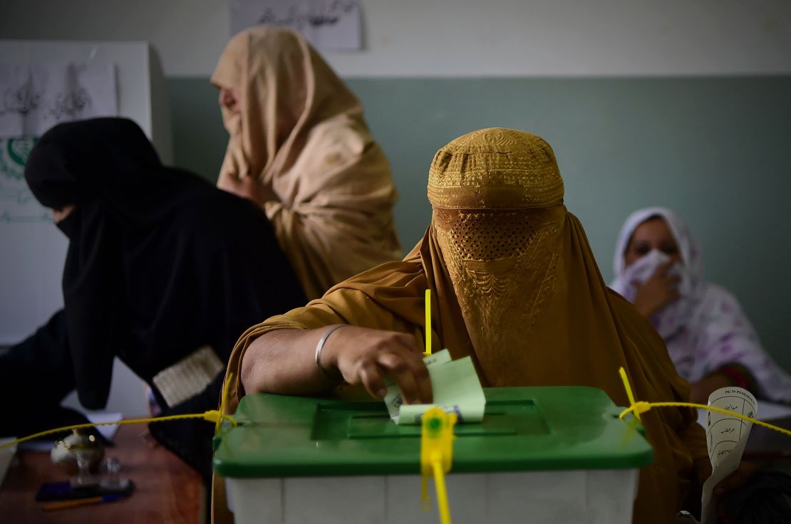 A burqa-clad woman casts her vote during Pakistan's general election at a polling station in Peshawar.