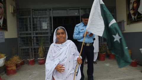 A Pakistani woman walks out of a polling station holding a national flag after casting her ballot.