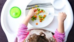 Above view of a little toddler child eats vegetables. Childhood and children health care concept.