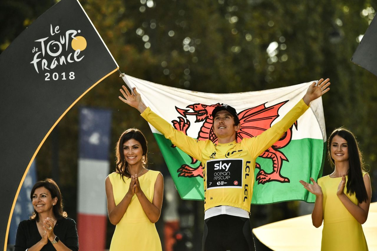Tour de France 2018 winner Geraint Thomas  holds the Welsh flag as he celebrates on the podium in Paris.