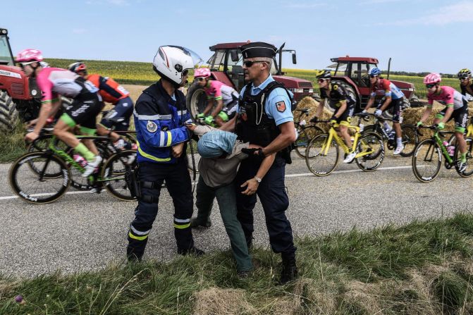 Gendarmes detain a protester as the pack rides behind during a farmers' protest at the Tour de France cycling race in southwestern France on Tuesday, July 24. The race was halted for several minutes  after tear gas was used as protesting farmers attempted to block the route. 