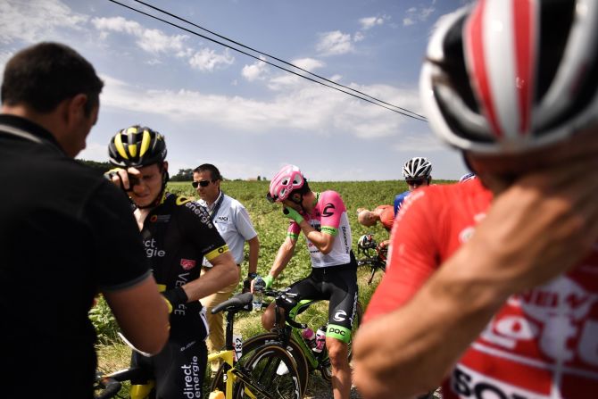 Riders react after riding through tear gas during a farmers' protest at the Tour de France cycling race in southwestern France on Tuesday, July 24.