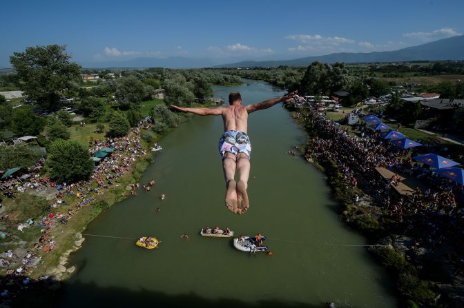 People look at a man as he jumps from the Ura e Shenjte bridge  during the annual traditional high diving competition near the town of Gjakova in western Kosovo on Sunday, July 22. 