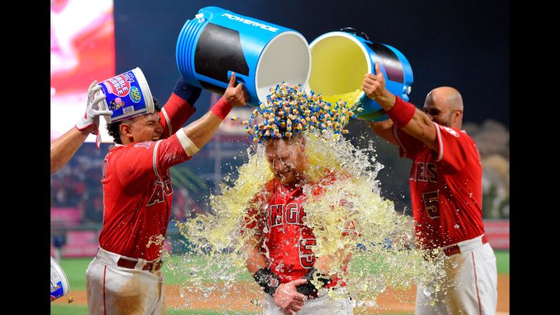 Los Angeles Angels' Kole Calhoun, center, is doused by Jose Briceno, left, and Albert Pujols, and showered with bubble gum by another player, after hitting a walk-off home run during the 10th inning of a baseball game against the Seattle Mariners on Friday, July 27, in Anaheim. The Angels won 4-3. 