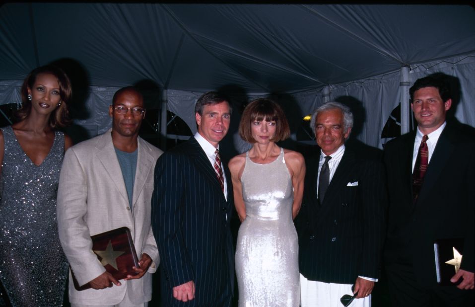 Wintour is flanked by designers Ralph Lauren (right) and Tommy Hilfiger (left) at an event in 1990. Model Iman is at far left.