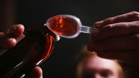 Man pouring cough mixture onto plastic spoon. Universal Images Group/Getty Images