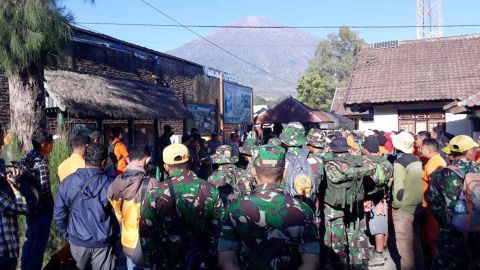 Indonesian soldiers and rescue teams gather to prepare for evacuating tourists from Mount Rinjani, seen in the background, at Sembalun in East Lombok on Monday.