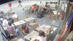A screengrab from CCTV footage at a cafe in Paris shows an interaction between a woman and a man who *allegedly* harassed her. CNN has applied a light blur to the faces of bystanders to protect their identities.