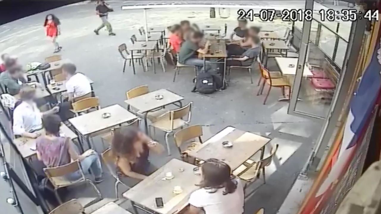 A screengrab from CCTV footage at a cafe in Paris shows an interaction between a woman and a man who allegedly harassed her. CNN has applied a light blur to the faces of bystanders to protect their identities.
