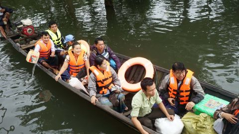 Burmese citizens wearing bright orange vests board rescue boats.