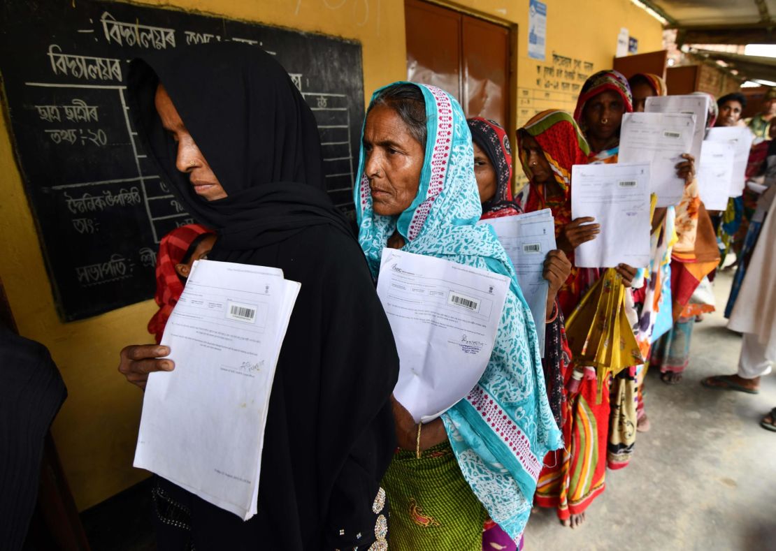 Residents hold their documents as they stand in a queue to check their names on the final list of National Register of Citizens.