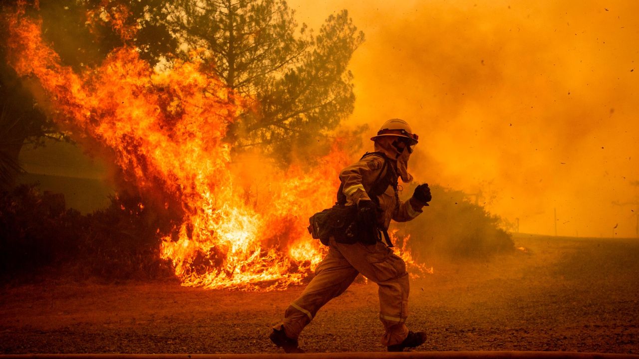 A firefighter runs while trying to save a home as a wildfire tears through Lakeport, Calif., Tuesday, July 31, 2018. The residence eventually burned. Firefighters pressed their battle against a pair of fires across Mendocino and Lake counties. In all, roughly 19,000 people have been warned to flee and 10,000 homes remain under threat. Noah Berger/AP