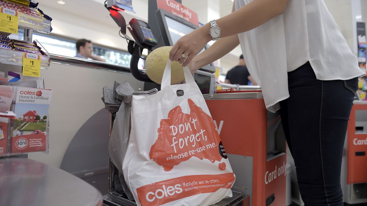 A customer places grocery items into a plastic bag at a self checkout counter in a Coles supermarket in Melbourne.
