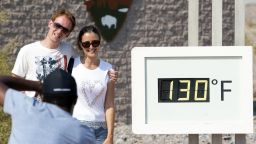 FILE - In this Thursday, July 26, 2018 file photo, a couple poses at the Furnace Creek Visitor Center thermometer in Death Valley National Park, Calif. The thermometer is not official and often very inaccurate, but is a popular photo spot. Preliminary data show that Death Valley set the world record for hottest month in July. National Weather Service meteorologist Todd Lericos says the month's average temperature at Furnace Creek in Death Valley was 108.1 degrees Fahrenheit (42.28 Celsius). That eclipses the previous record, set in Death Valley during July 2017 when the average was 107.4 degrees F (41.89 C). (Richard Brian/Las Vegas Review-Journal via AP, File)