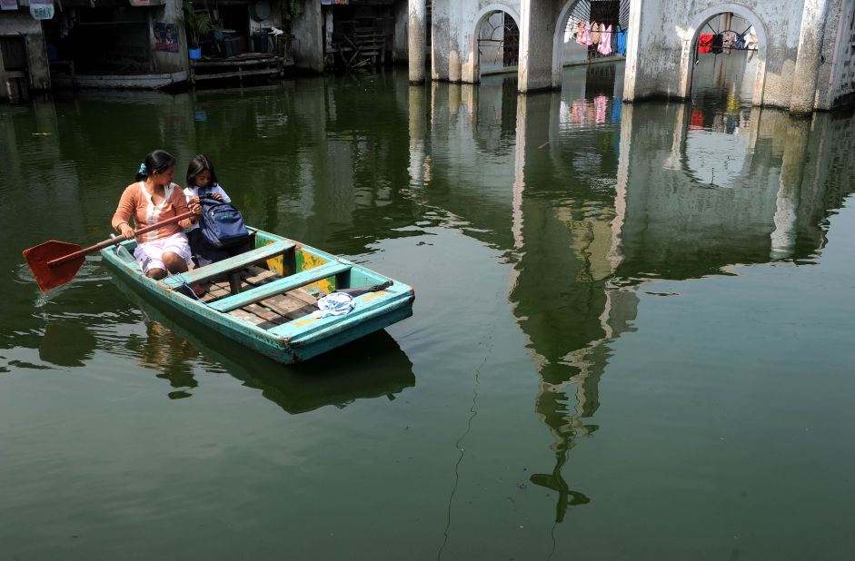 Claire Anne Tuazon takes her 8-year-old daughter, Genesis Tuazon, to school in a rowboat in the City of Malabon in the Philippines.