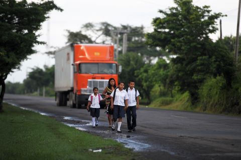 Silvia Alvarado, walks to school with her sister Rosario and brother Henry, accompanied by their mother Nuya, in the village of Metalio in El Salvador.