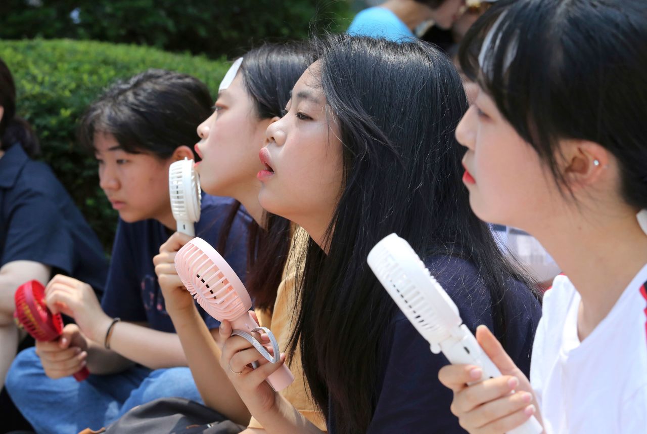 People use portable fans to cool down during a rally in Seoul, South Korea, on Wednesday, August 1. It was the hottest day in Seoul in 111 years, according to the Korean Meteorological Administration.