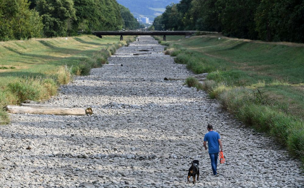 A man walks his dog in the dry riverbed of the Dreisam in Freiburg, Germany, on August 1.