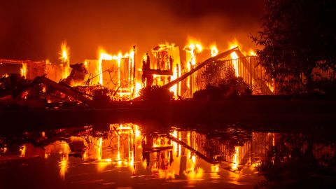 A burning house is reflected in a pool in Redding, California, as the Carr Fire raged in late July. 