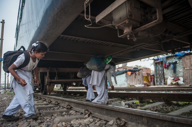 Children cross a stationed train during their school commute in Delhi, India. 