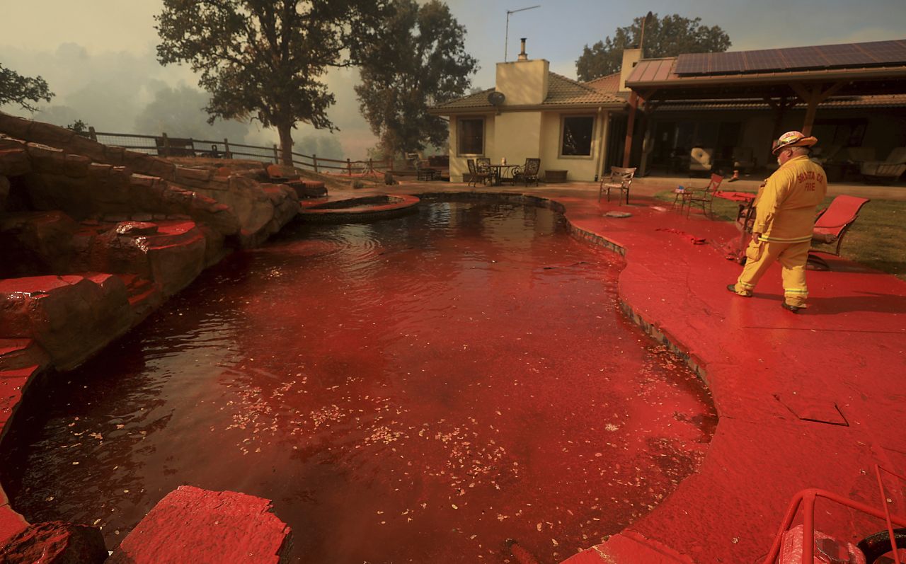 A firefighter walks around a swimming pool that had been sprayed by fire retardant near Lakeport.
