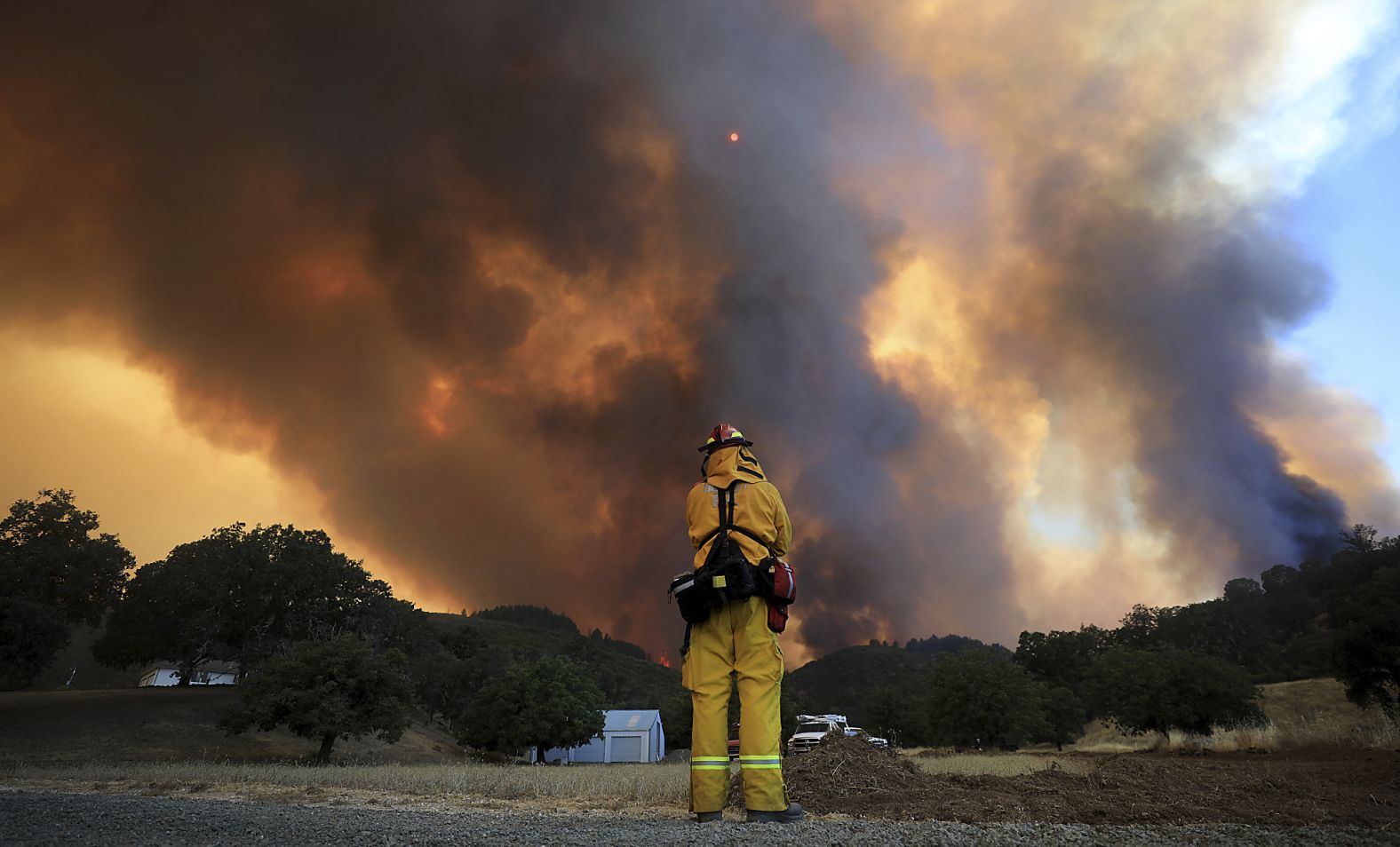 A tower of smoke pours from Cow Mountain as a firefighter keeps a watch on surrounding vegetation.