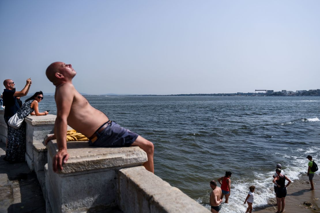 A man sunbathes Friday as others cool off in the Tagus River in Portugal's capital, Lisbon.