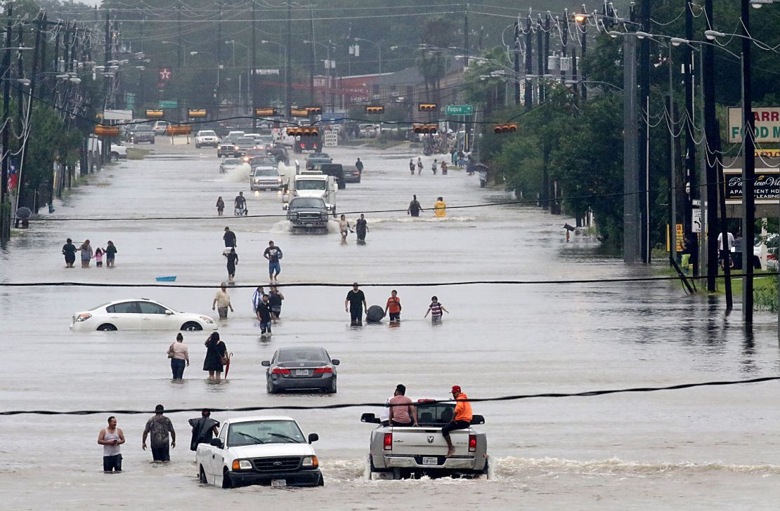 People walk through flooded roads in Houston, Texas, on August 27, 2017 as Hurricane Harvey hit the city.