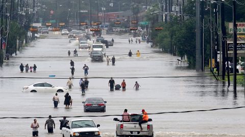 People walk through flooded roads in Houston, Texas, on August 27, 2017 as Hurricane Harvey hit the city.