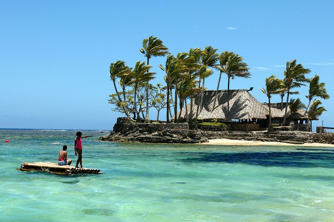 Melanesian children float on a bamboo pontoon by Wicked Walu Island on the resort-studded Coral Coast of Fiji.