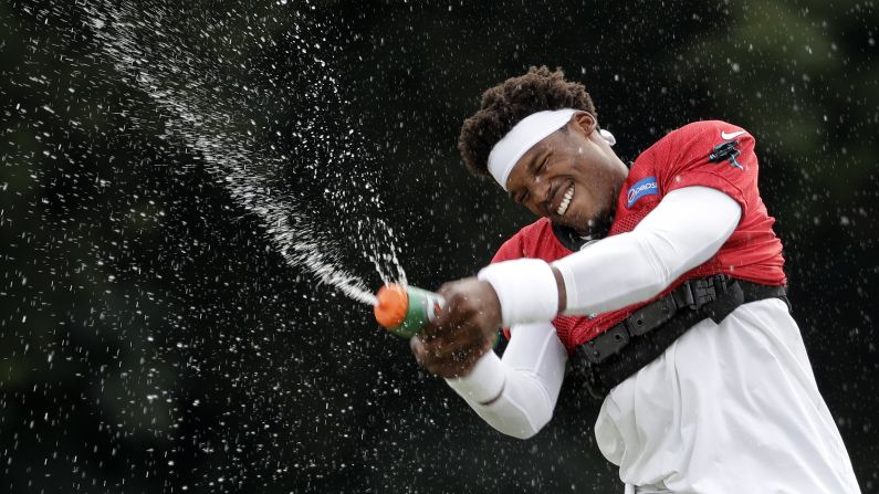 Carolina Panthers' Cam Newton squirts water from a bottle as he warms up during practice at the team's training camp in Spartanburg, South Carolina on Monday, July 30. 