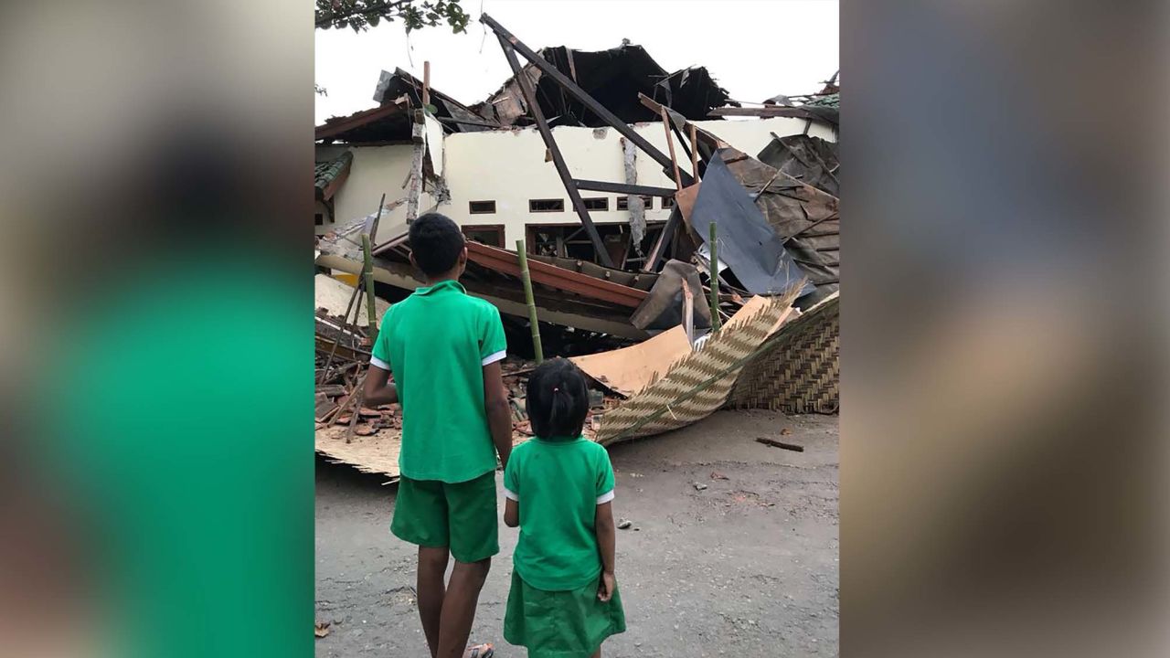 Children from the Peduli Anak Foundation stand outside the destroyed home.