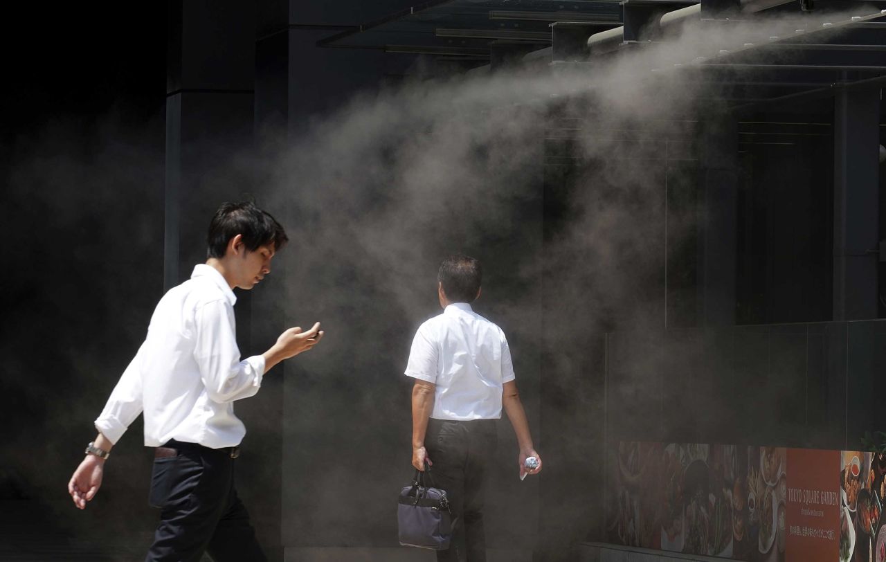 People cool down under a mist in Tokyo on Monday, August 6.
