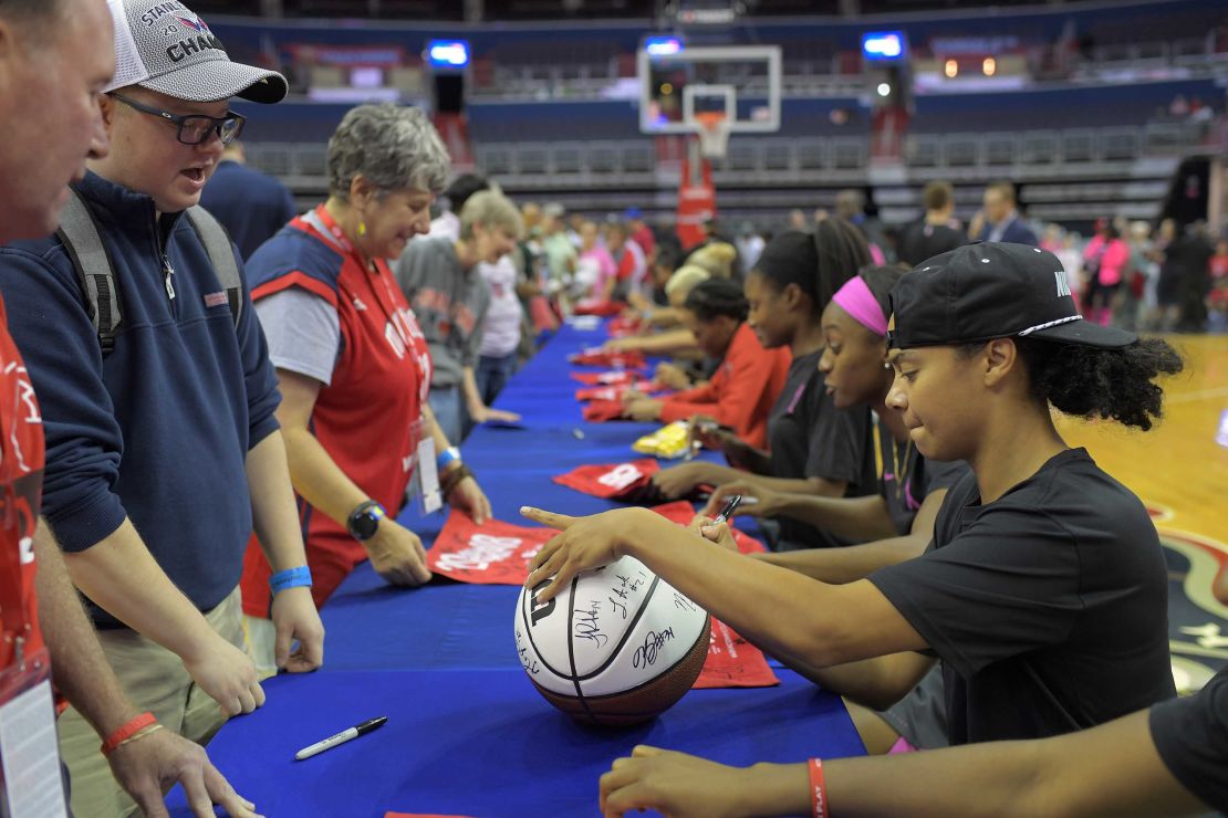 Washington guard Kristi Toliver, right, signs a basketball along with her other teammates at a long table on the floor after their game got canceled between the Washington Mystics and the Las Vegas Aces in Washington DC on Friday.