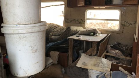 The cluttered compound included a partially buried camper trailer.