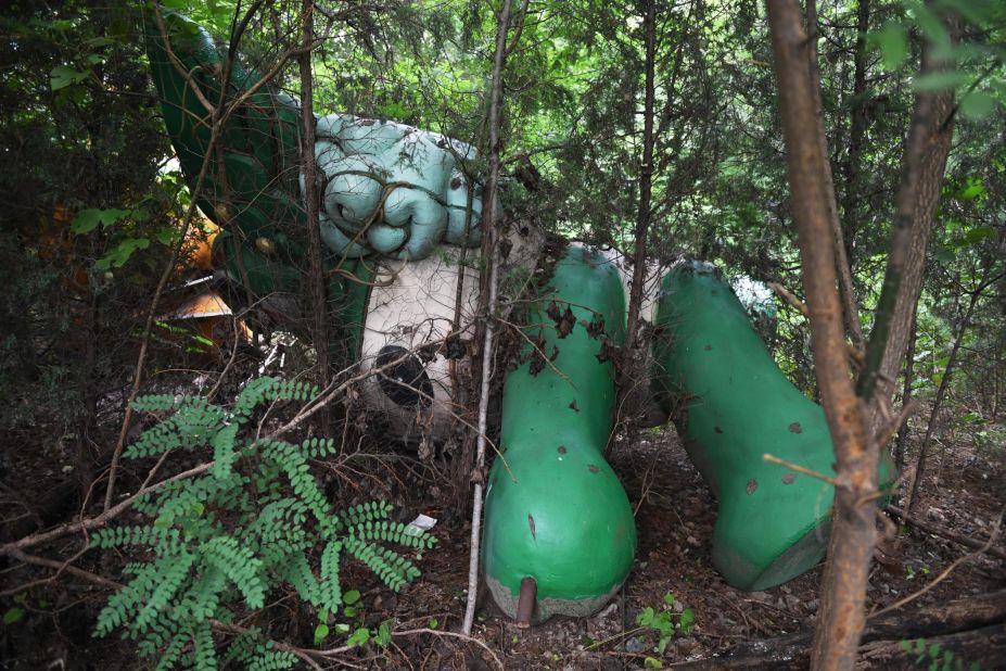 <strong>Reclaimed by nature: </strong>Nini, another of the mascots for the Games, is seen lying among trees behind the abandoned, never-completed mall in Beijing.
