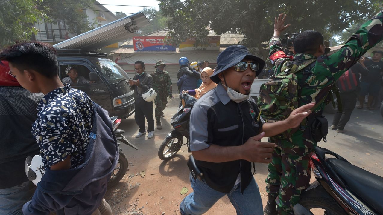 A soldier and an official try to calm people following an aftershock Thursday on Lombok.