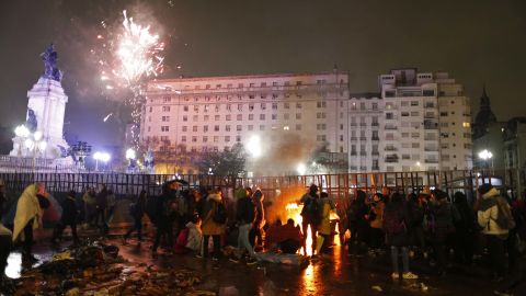 Abortion rights activists gather around a bonfire to keep warm as celebratory fireworks go off in the distance.