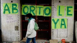 A woman walks past a sign reading "Abortion now" in Buenos Aires, Argentina Wednesday, Aug. 8, 2018. Following months of increasingly tense debate, lawmakers in Argentina meet in Congress on Wednesday ahead of a vote on a bill that would decriminalize abortions up to the first 14 weeks of pregnancy.(AP Photo/Natacha Pisarenko)
